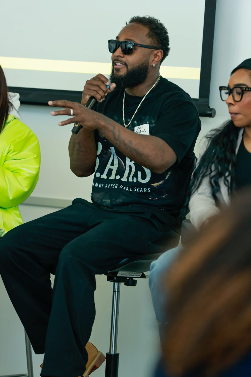 Tank on a stool with a microphone, speaking to the room